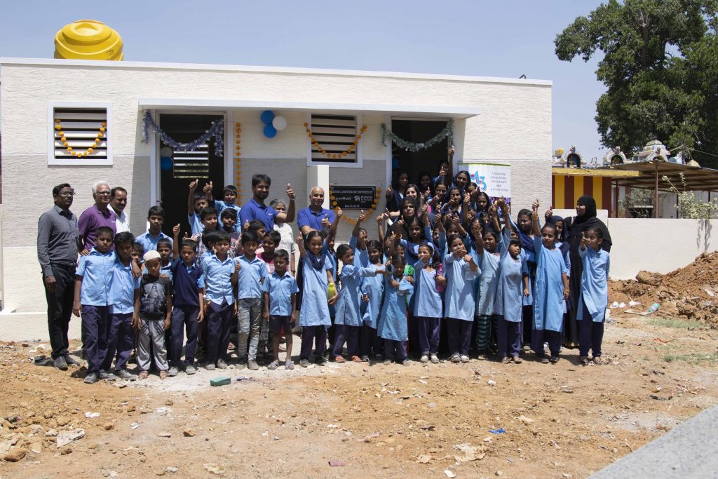 Indian primary school children in front of a toilet block