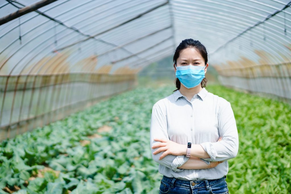 asian woman in mask inside greenhouse